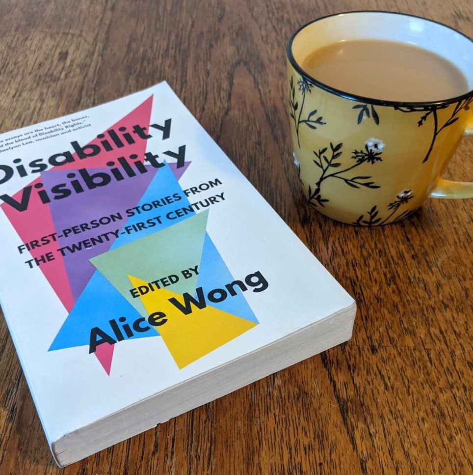 Paperback copy of 'Disability Visibility', edited by Alice Wong, next to a cup of tea